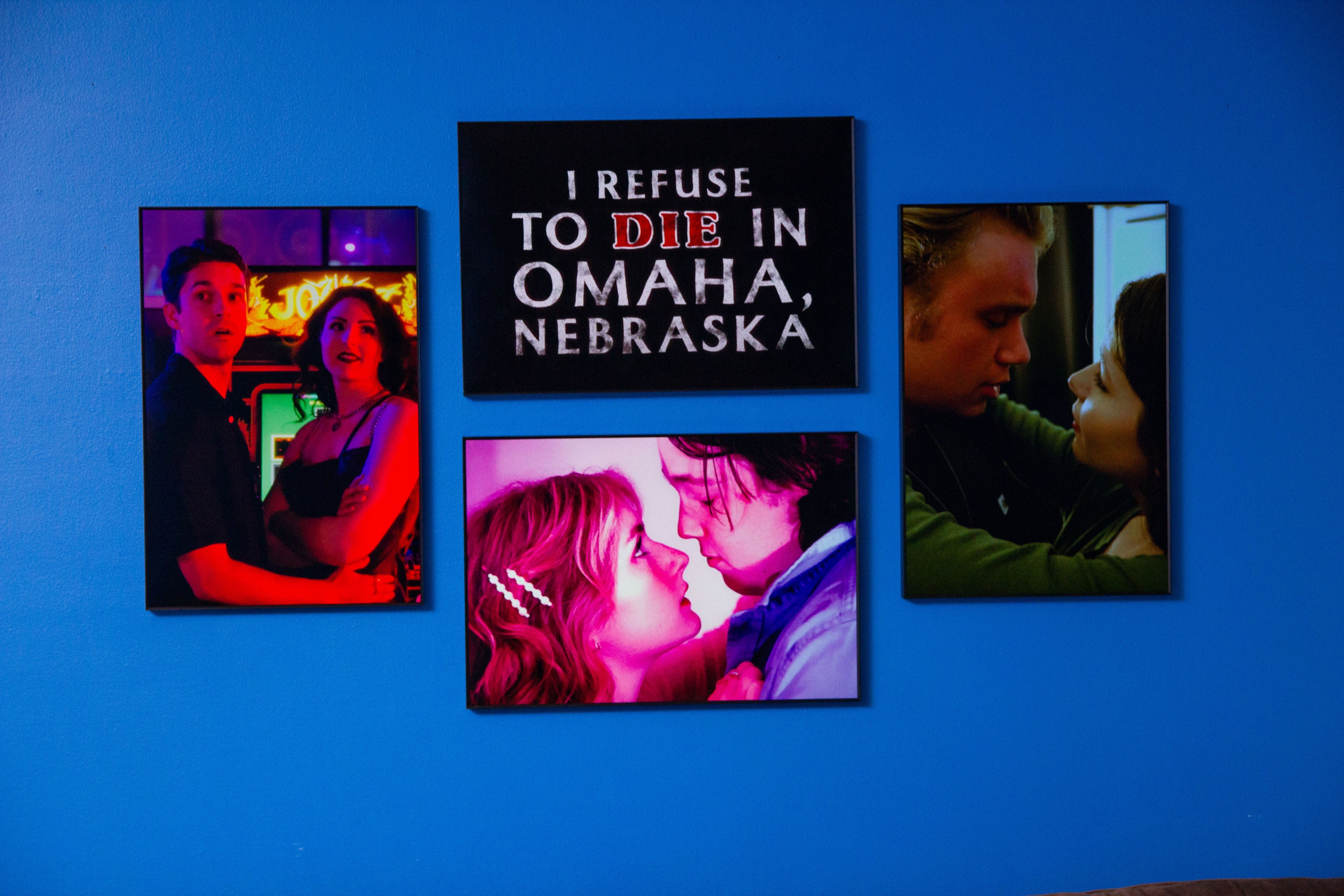 Four framed movie posters on a blue wall with 'I Refuse to Die in Omaha, Nebraska' prominently displayed.